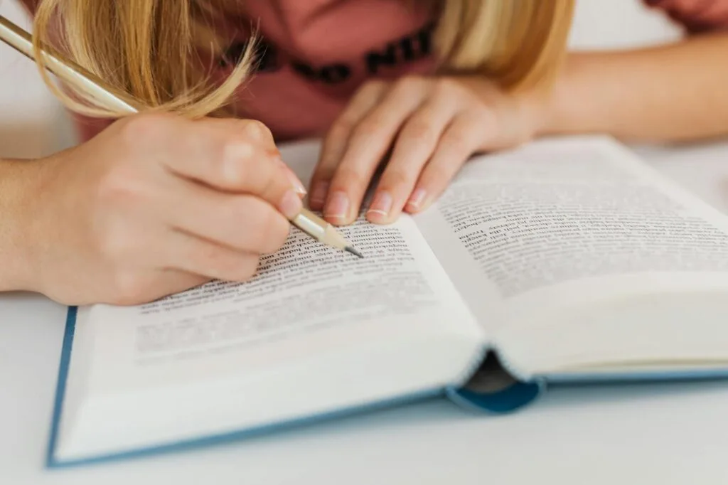 woman reading and writing in book with pencil