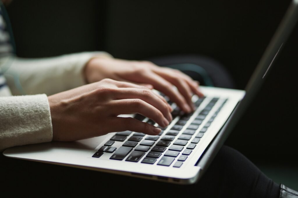 Close-up of hands typing an email to a professor on a laptop